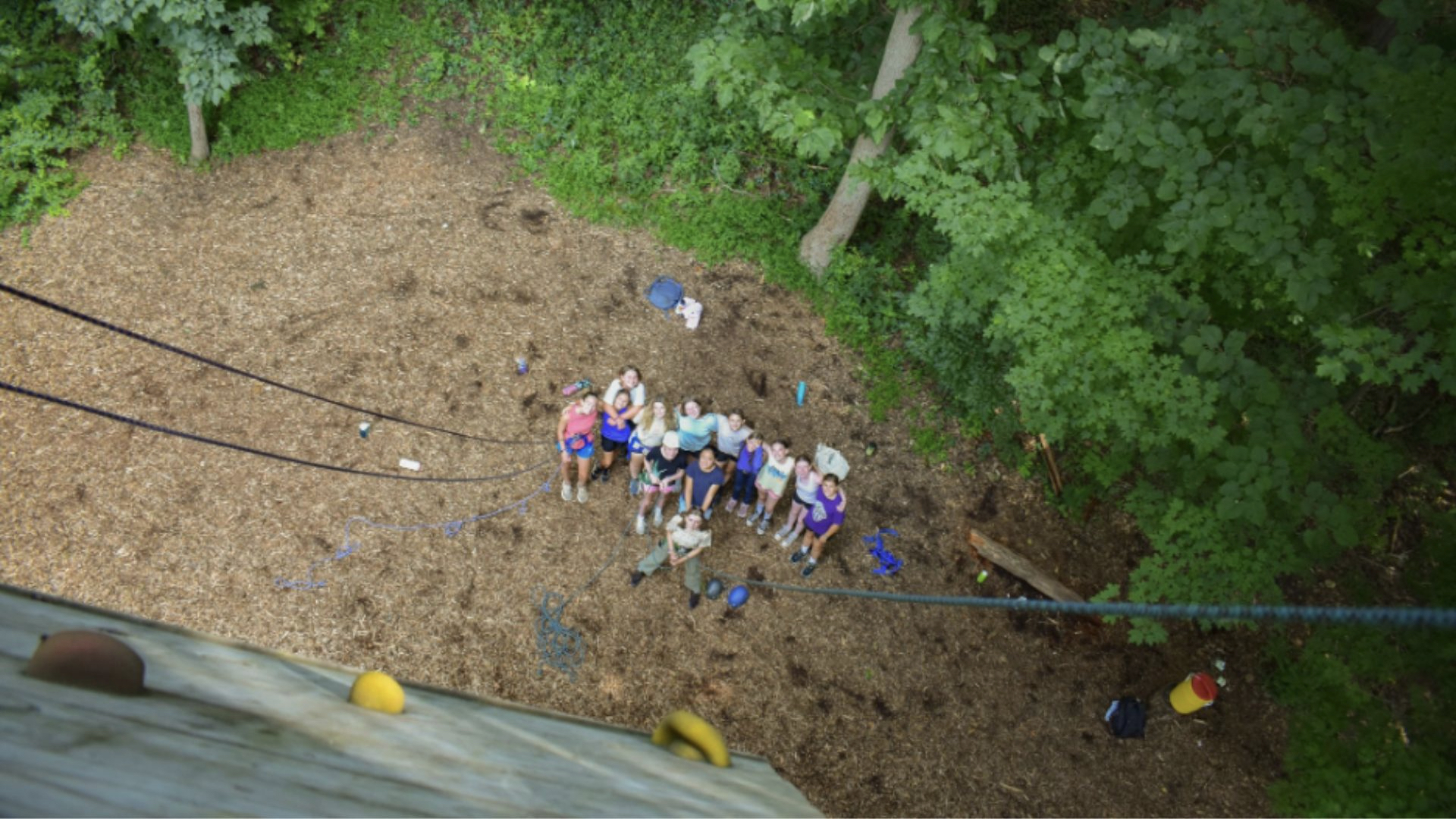 View from the top of a climbing wall, showing a group of people looking up. 
