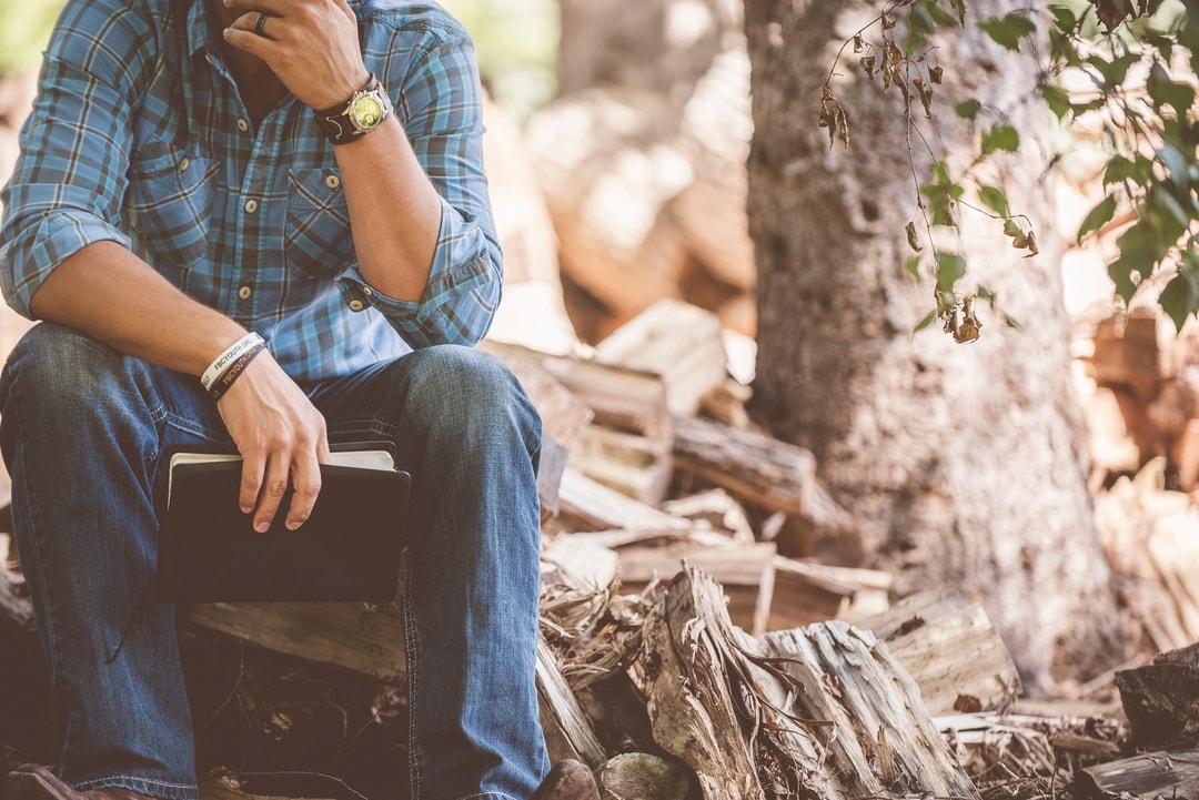man-sitting-in-woodchips-holding-bible