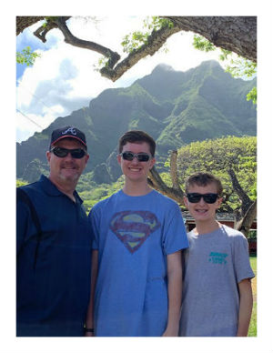 Hunter, Chris, and Ethan Thompson preparing to zipline in the Hawaii mountains